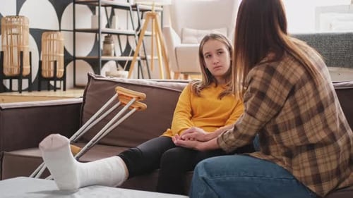 Woman Comforts Teen Girl With a Leg Cast