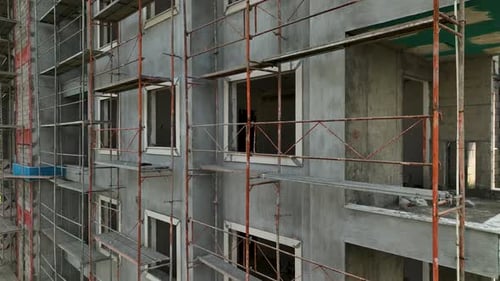 Los constructores trabajan de frente al edificio, se apoyan en el andamio