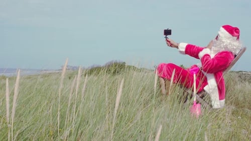 Santa Claus Making a Video Call at the Beach