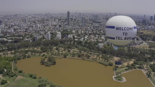 Aerial Shot Of Hot Air Balloon Descending Over Yarkon Park Against Sky In City