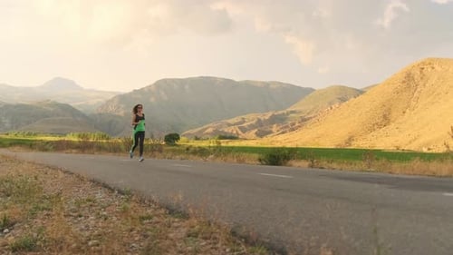 Athlete Runs Down a Road at Sunset Building Endurance for Races