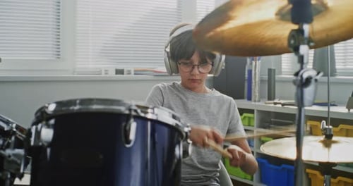 Talented Boy Wearing Headphones Playing Drums in Percussion Class of Elementary School