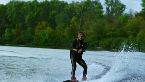 Stylish man wakeboarding on river during summer extreme holidays in slow motion