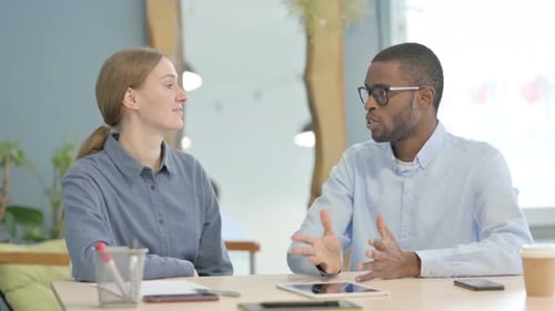 Talking Young Business People Sitting in Office