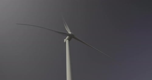 Wind turbine from bellow and in front, head spinning with blue sky background
