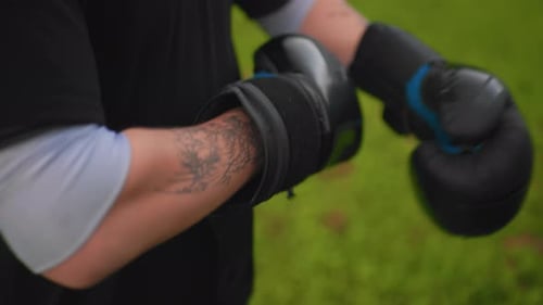 Man Putting on Boxing Gloves Outside on Grass