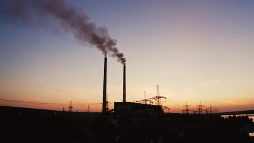 Factory tubes on the sunset background. Smoke from the pipes. Pollution concept. Video from the air.
