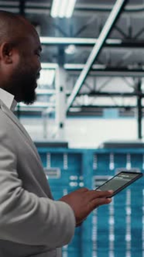 Vertical Video Cheerful Server Room Engineer Troubleshooting Backend Operations Using Tablet