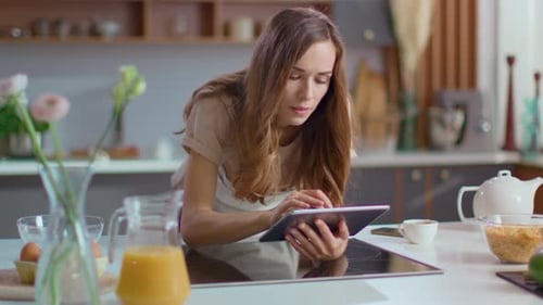 Woman Uses Tablet in Modern Kitchen Environment