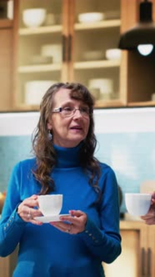 Woman Drinks Coffee and Chats in Her Kitchen