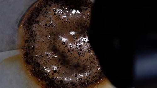 Barista verse de l'eau chaude sur du café dans un filtre en papier au ralenti extrême.