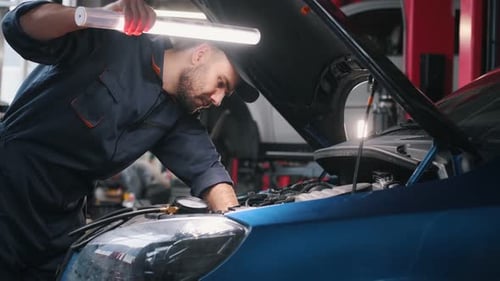 Lighting up the place, under the hood. Mechanic working in a car service station.