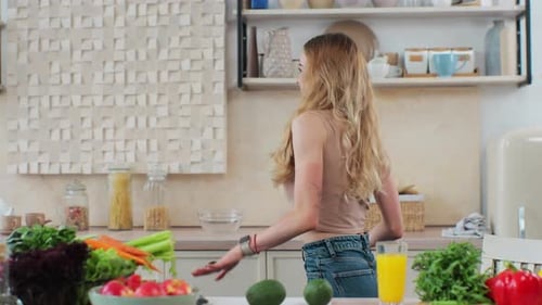Young Woman Dancing in Kitchen with Vegetables
