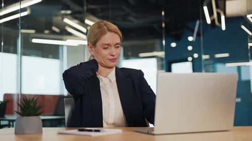 Tired Businesswoman is Experiencing Neck Pain While Working in Modern Office