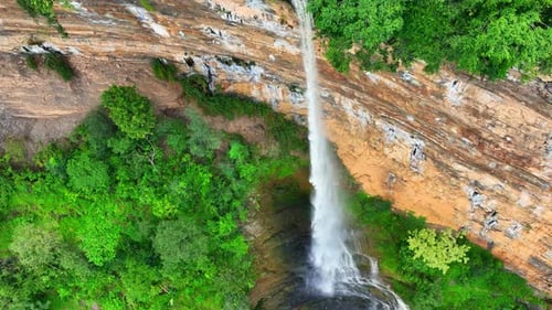 Drone captures majestic waterfall cascading from cliff.