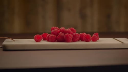 A Collection of Vibrant Red Raspberries Neatly Arranged on a Clean White Cutting Board