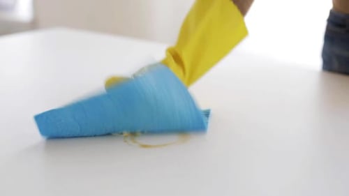Man Wipes White Table with Blue Cloth