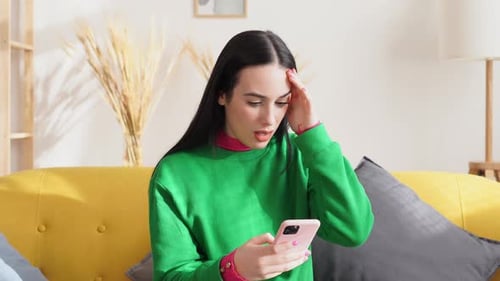 Woman Looks Concerned at Phone on Couch