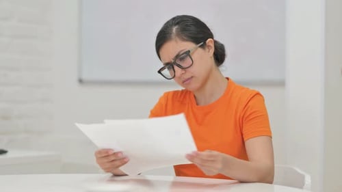 Frustrated Woman Reviews Documents at Table