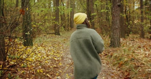 Young Woman in a Yellow Beanie Walking Two Dogs on a Path in the Autumn Forest