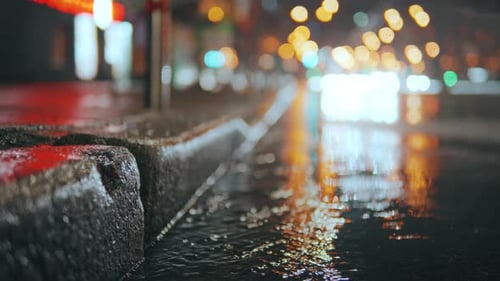 Raindrops Fall on Multicolored Asphalt Illuminated By Street Lamps