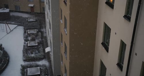 Heavy snow falling in front of apartment windows in city, slow motion