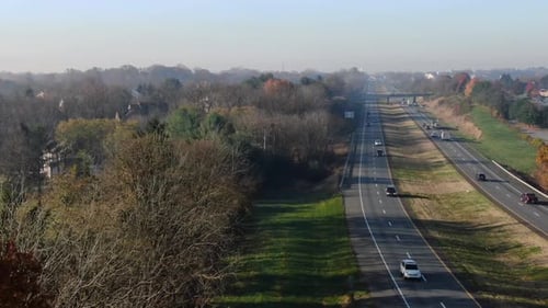 Aerial truck shot of traffic above American highway in USA, United States of America. Autumn trees d