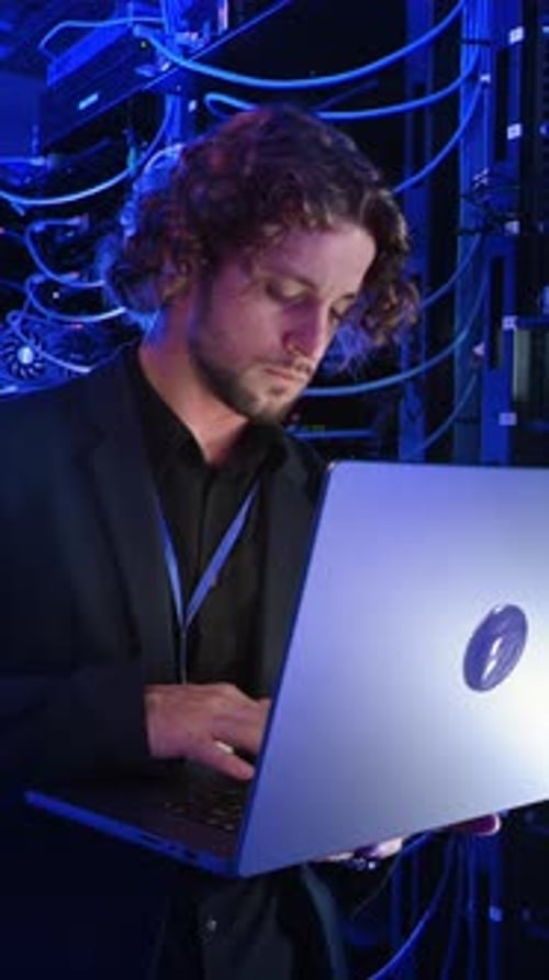 Man with Laptop in Blue Lit Server Room