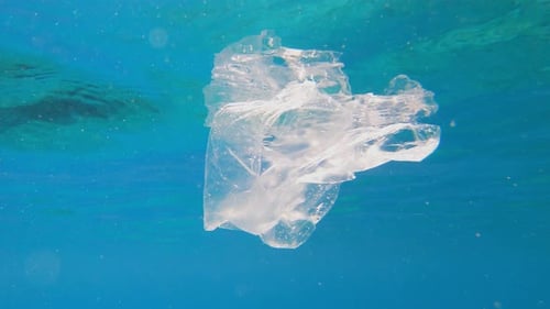 Plastic pollution in sea ocean - big environmental problem. Plastic bag and bottle floating in sea.
