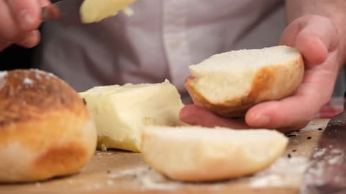 Hands Spreading Butter on Bread Roll Close Up