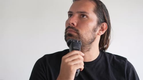 Man Shaving Beard with Electric Razor at Home