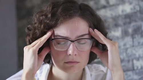 Woman Massaging Temples with Headache Indoors