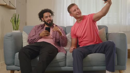 Friends Relaxing with Cellphones on Couch at Home
