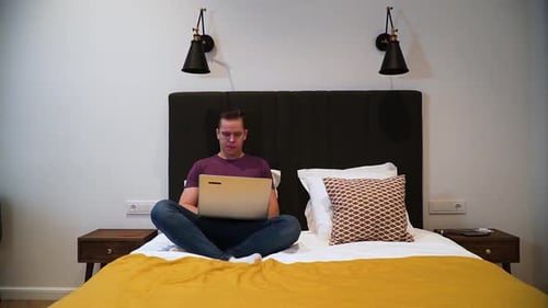 Young Adult Opens Laptop in Hotel Bedroom