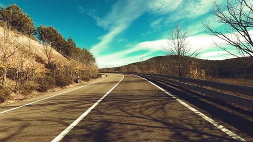 Driving vehicle on a long asphalt straight road in the nature with blue sky