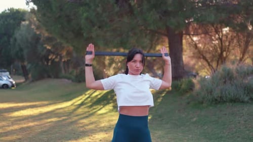 Sporty Woman Exercising with Resistance Band at City Park