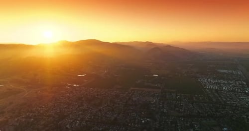 City with densely built architecture of low houses at sunset. Bright sun hiding behind the mountains