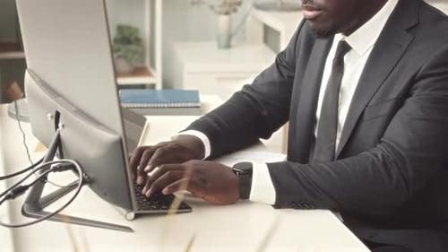 Man in Suit Typing at Computer in Office