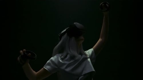 Woman in VR Headset Holding Controllers in Dark Room