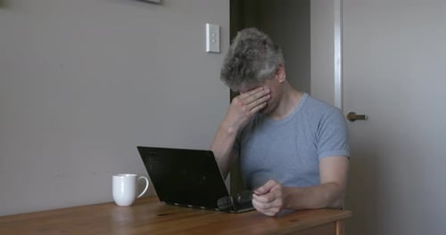 Tired Man Working from Home on Laptop