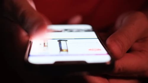 Hands Scroll Through Mobile Phone At Night