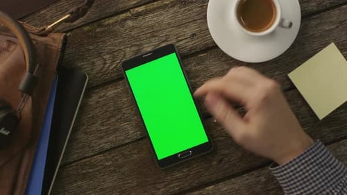 Usando o telefone Android que está deitado na mesa de madeira em casa. Vista superior. Estilo de vida causal