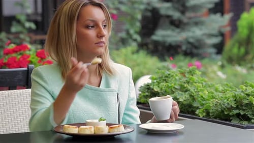 Woman Enjoys Cakes and Coffee at Cafe