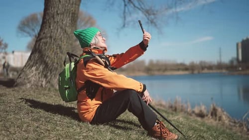 Aged Woman Traveler Resting After Walk in City Park and Taking Selfie By Phone Active Lifestyle in