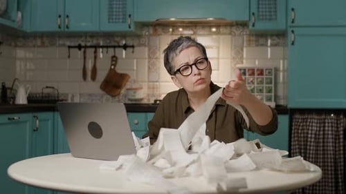 Woman Managing Home Finances Holding Receipts Using Laptop