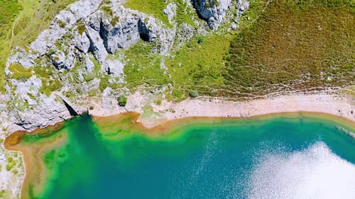 Descend above the deep turquoise lake with clear water reflecting bright sunlight.