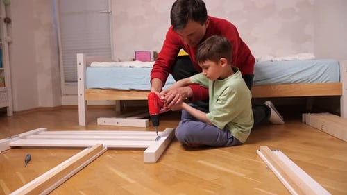 Man and Boy Constructing Bed Frame Together