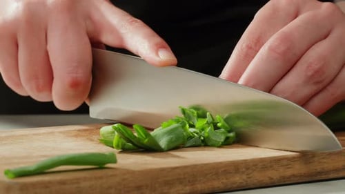 Chef Cutting Bunch of Green Onion Feathers By Knife on a Cutting Board on Professional Restaurant
