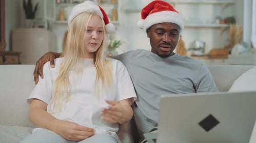 Couple wearing Santa hats using laptop at home