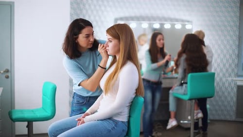 Makeup Artist Applying Cosmetics in Bright Studio